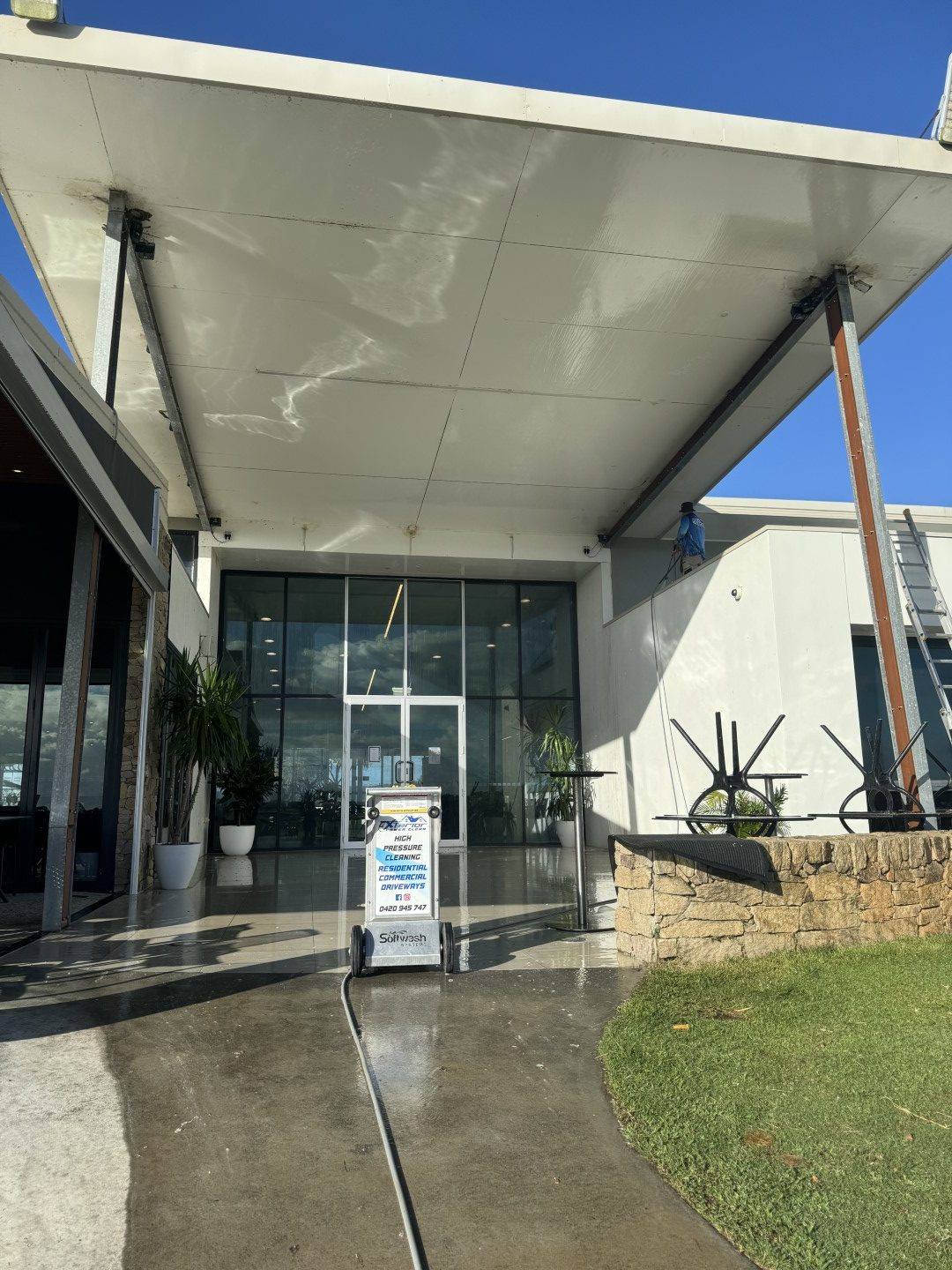 Xterior Power Clean soft washing a large cantilevered awning over a commercial entrance