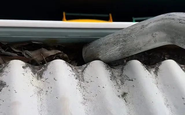 Blocked roof gutter full of leaves and debris before Xterior Power Clean vacuums it out
