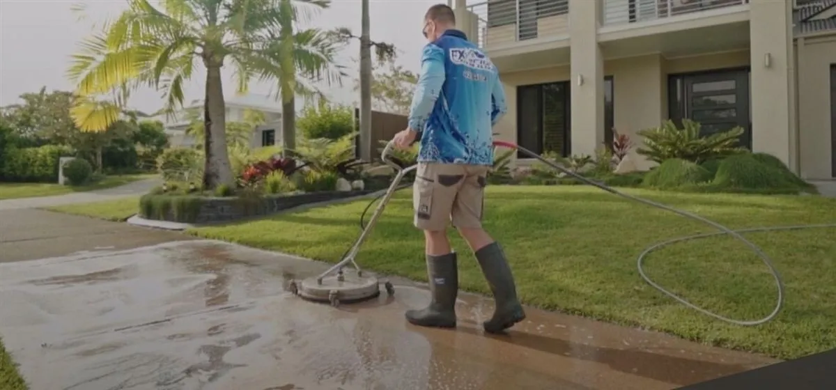 Technician pressure cleaning a brick paver driveway