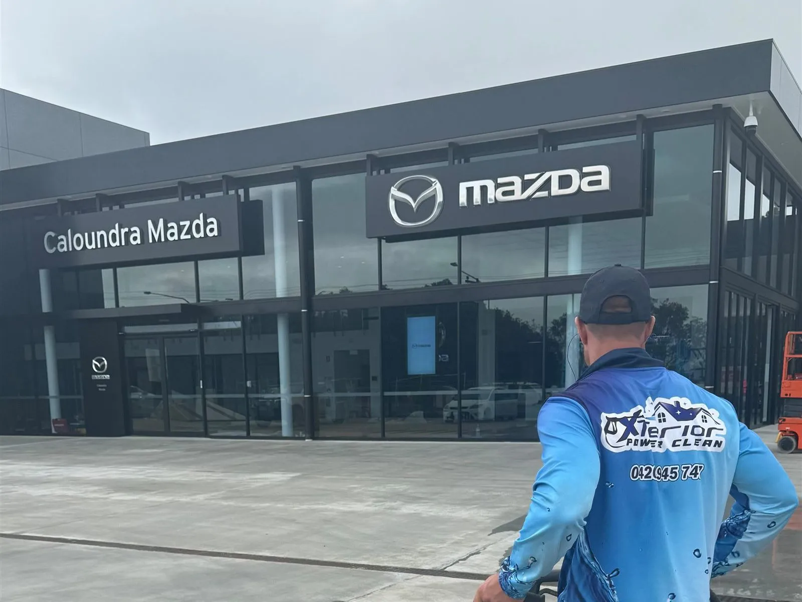Xterior Power Clean technician pressure cleaning the forecourt at Caloundra Mazda