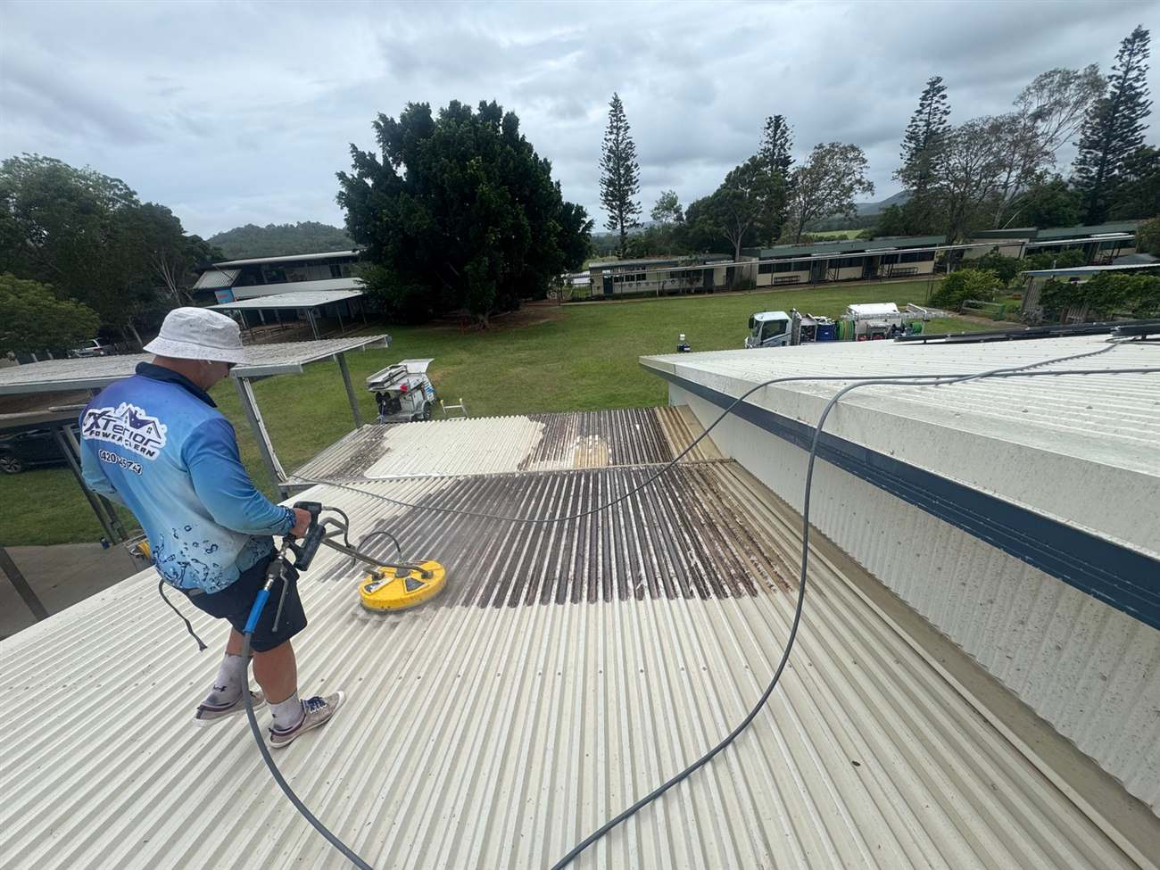 Technician high-pressure cleaning a metal roof
