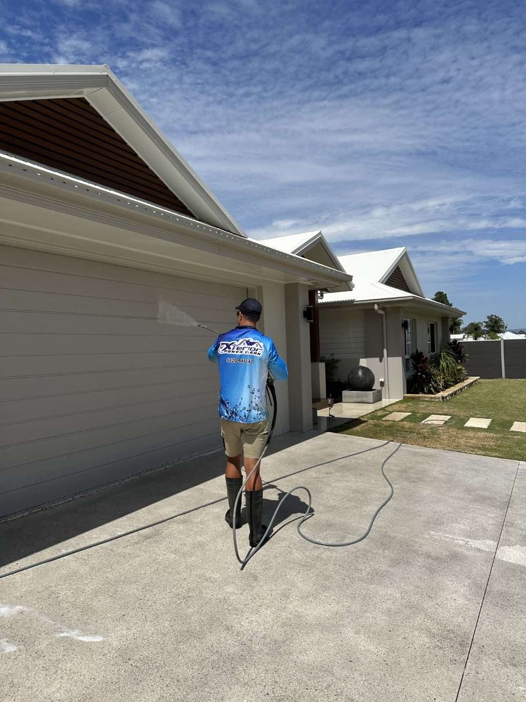 Technician soft washing a house exterior