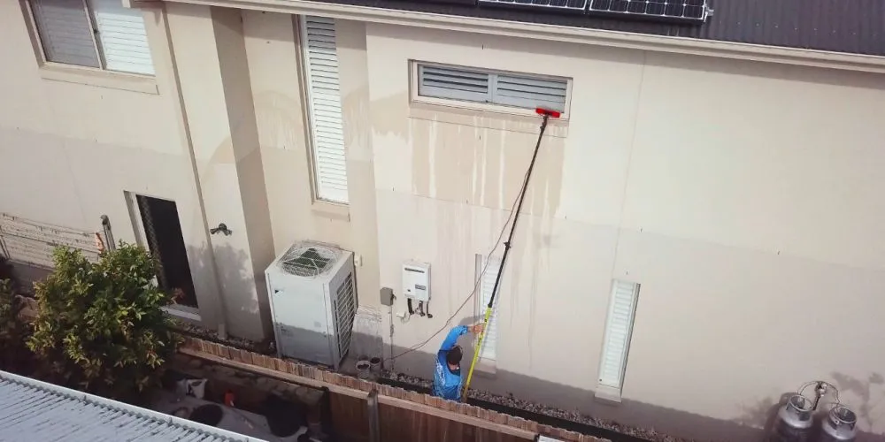Soft washing a rendered wall with a water-fed pole