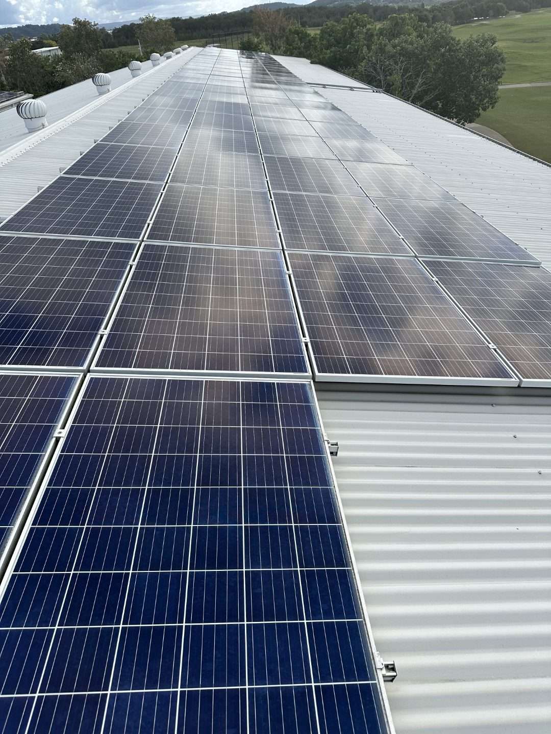 Rows of solar panels on a commercial roof, half of them cleaned