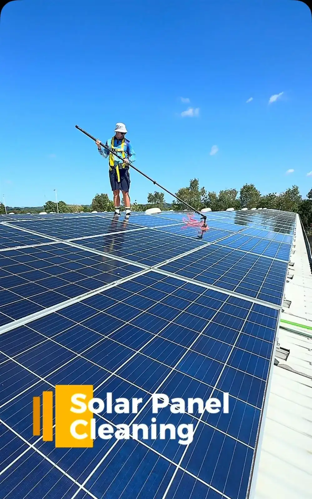 Harnessed technician cleaning a commercial rooftop solar array